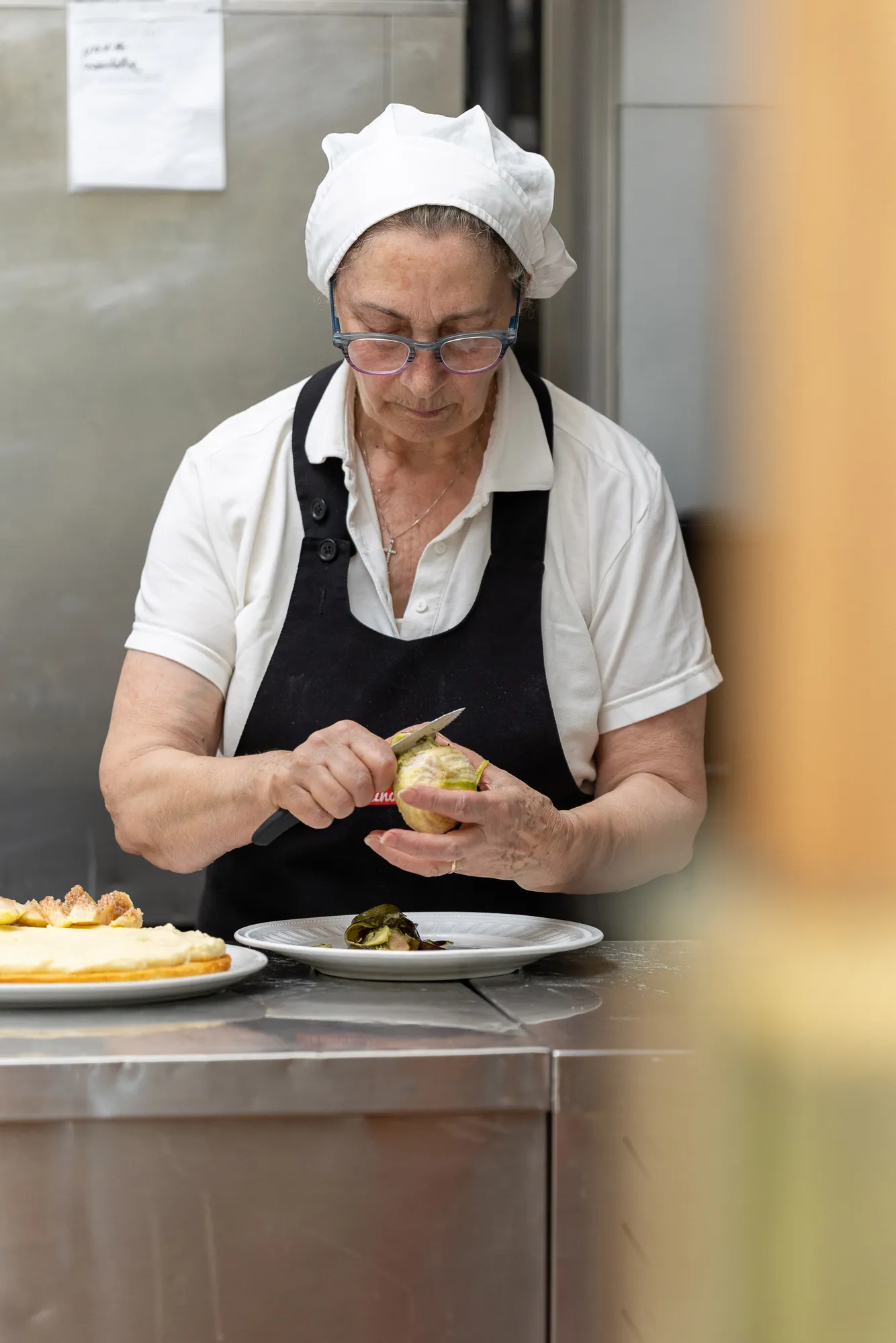 Una cuoca pulisce i carciofi in cucina