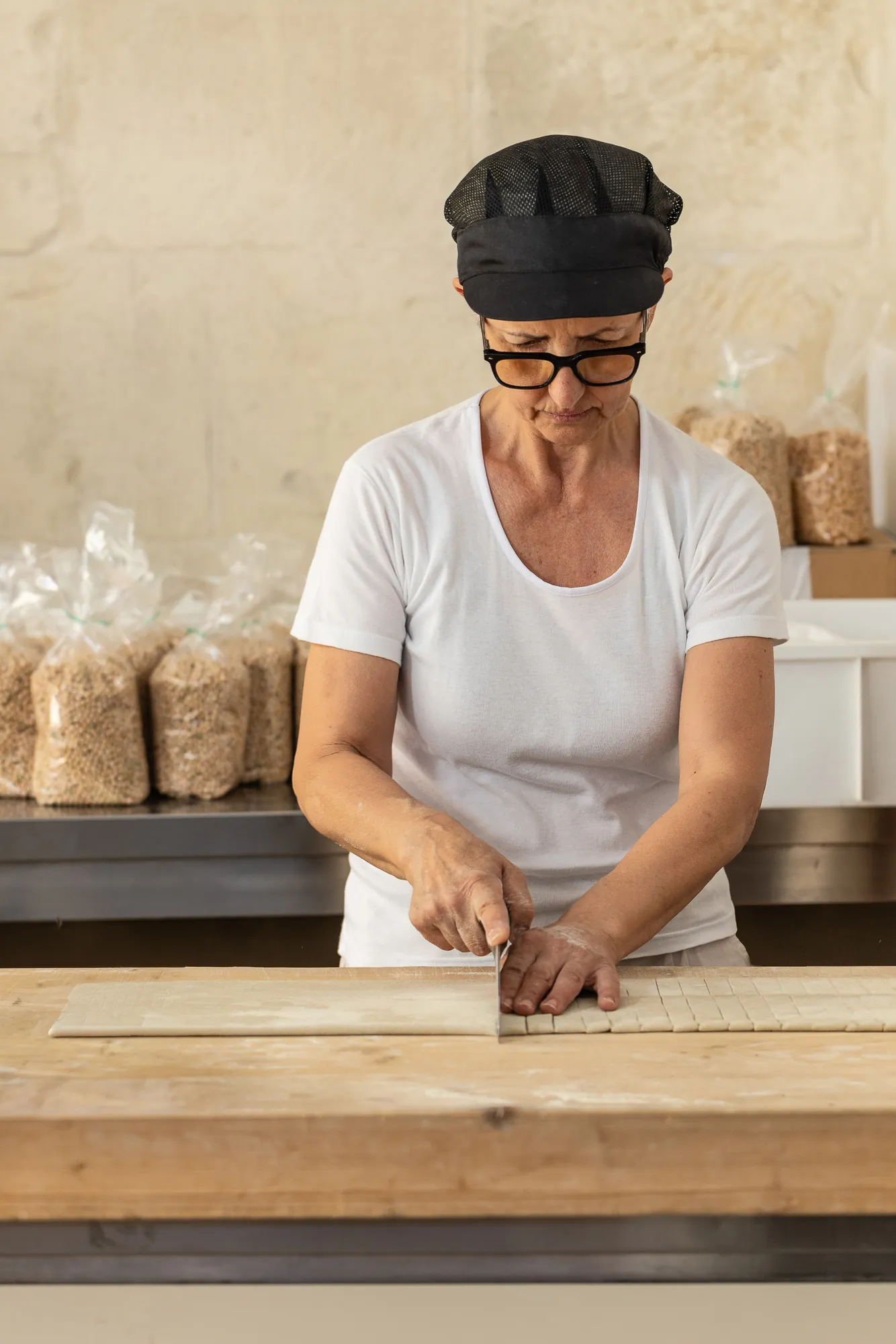 Una cuoca taglia la pasta fresca sul tagliere
