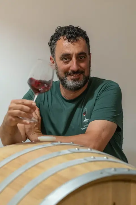 Il vignaiolo con un calice di rosso, appoggiato a una botte