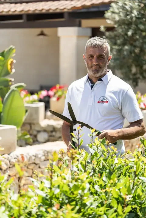 Il giardiniere con le cesoie tra le aiuole fiorite