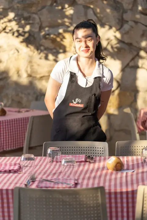 Una cameriera sorridente accanto ai tavoli all'aperto