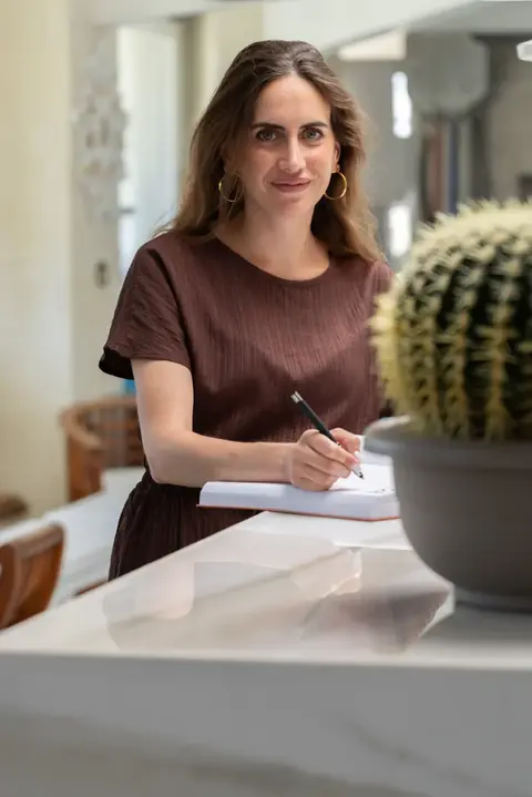 Una ragazza prende appunti al bancone, accanto a un cactus