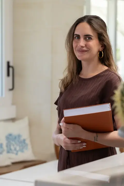 Una ragazza sorridente con un libro tra le mani, nella hall