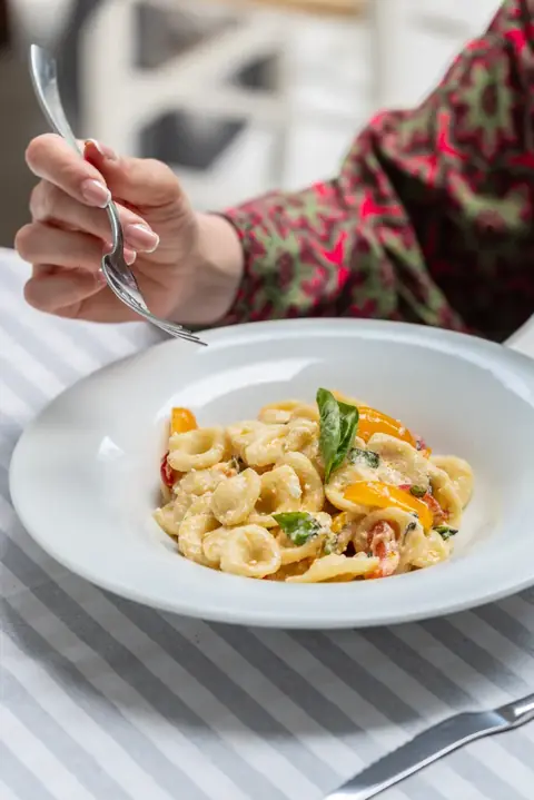 Un piatto di orecchiette con pomodorini e basilico