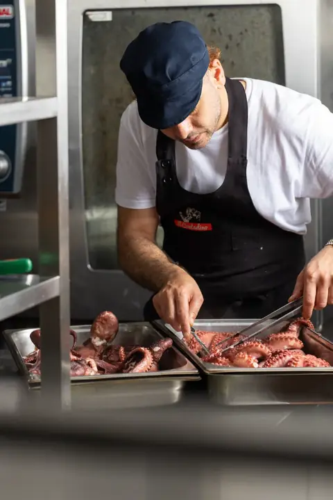 Un cuoco pulisce i polpi in cucina