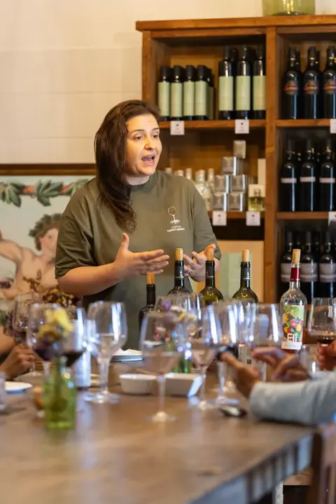 Una degustazione di vini in sala, davanti agli scaffali delle bottiglie